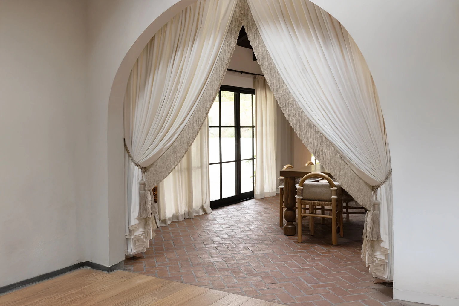 Close-up of curtain tie back tassels in a modern rustic dining space, highlighting pleated curtains and textured trims.